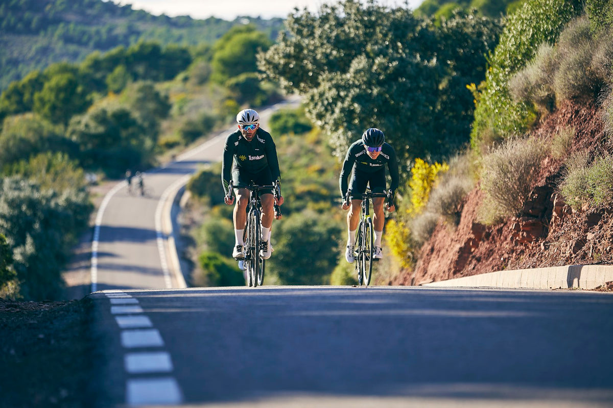Two cyclists riding on a mountain road. Editorial photograph from Tuvalum on Unsplash, not a product or customer photograph.